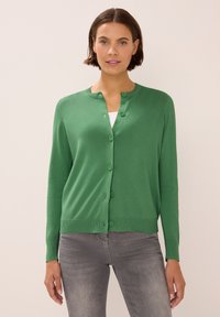 Zelený pletený kardigan s kulatým výstřihem, zapínáním na knoflíky a žebrovaným lemem. Látka se zdá být hladká a lehká.