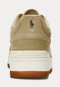 Béžová semišová běžecká obuv s bílou podrážkou, hnědou vnější podrážkou, logem Polo Ralph Lauren a embosovaným textem "Ralph Lauren" na mezipodešvi.