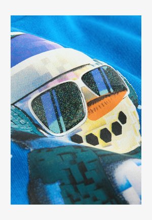 Sinivärviline dressipluus, millel on graafika lumememmest, kes kannab prille, millel on sädelevaid objektiive, oranž porgandist nina ja mustad nupumaised detailid.