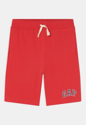 Punaiset rennot shortsit, joissa valkoinen säädettävä kiristysnyöri vyötäröllä ja "GAP"-logo vasemmassa lahkeessa, sivutaskuilla.