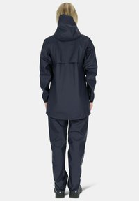 Marine waterdichte jas met capuchon en elastische boorden, gecombineerd met bijpassende broeken. Glad textuur en functioneel ontwerp voor gebruik buitenshuis.
