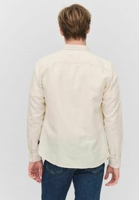 Witte lange mouw shirt met een gebogen zoom, knoopmanchetten en een subtiele textuur. Gekozen in combinatie met donkerblauwe jeans.
