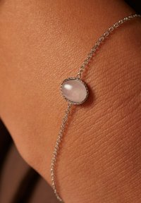 Silver chain bracelet featuring an oval rose quartz gemstone. The chain is delicate with circular links, and the stone has a smooth, translucent surface.