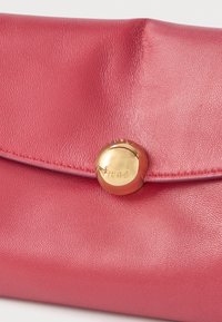 Różowa skórzana kopertówka o fakturowanej powierzchni, z złotym zapięciem na zatrzask oraz tłoczonym logo marki.