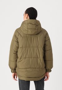 Casaco puffer verde-oliva com capuz, apresentando um design acolchoado, punhos elásticos e um corte ligeiramente oversized para calor e conforto.