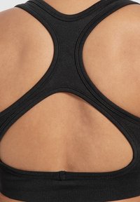 Schwarzer Sport-BH mit Racerback-Design, aus dehnbarem Material gefertigt, das enge Nahtdetails und eine glatte Textur aufweist.