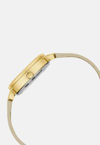 Orologio in metallo dorato con cassa rettangolare, quadrante in vetro trasparente e cinturino sottile. Presenta una corona circolare e un design minimalista.