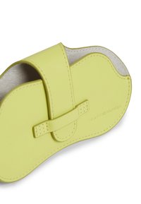 Κίτρινο δερμάτινο παντόφλα με στρογγυλεμένο σχήμα, διαθέτει λουράκι για κλείσιμο. Εσωτερικά έχει απαλό, ελαφρώς υφασμάτινο πάτο. Λογότυπο της μάρκας σκαλισμένο στο πλάι.