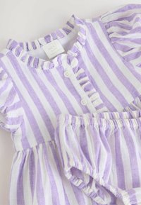 Lila och vit randig babyklänning med volangkrage, knappstängning och matchande shorts med elastisk midja. Tillverkad av lättviktsmaterial.