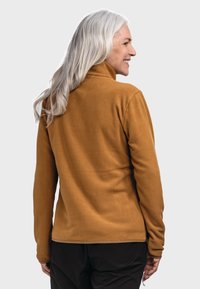 Fleecejacke in tiefem Senf mit hohem Kragen, glatter Textur und tailliertem Design, mit langen Ärmeln und geradem Saum.