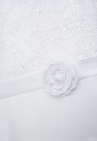 Weißer Stoff mit Blumenstickerei und Pailletten, mit einem akzentuierenden, mehrlagigen Stoffblumen. Glatte Textur und sanfter Glanz.