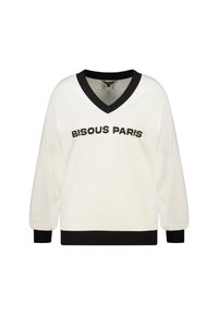Crèmekleurige sweater met zwarte V-hals en manchetten. "BISOUS PARIS" in dikke zwarte letters aan de voorkant gedrukt. Zachte textuur, ontspannen pasvorm.
