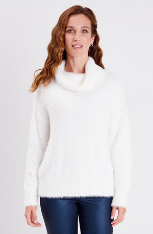 Weißer, flauschiger Pullover mit einem schlichten Ausschnitt und langen Ärmeln. Verfügt über gerippte Bündchen und Saum. Kombiniert mit dunkelblauen, glänzenden Hosen.