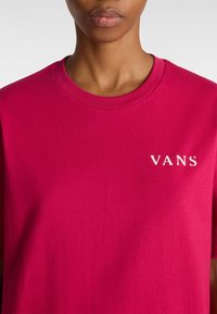 Fuchsiové bavlněné tričko s krátkým rukávem, vybavené kulatým výstřihem a bílým nápisem "VANS" na levé straně hrudi. Hladká textura a pohodlný design.