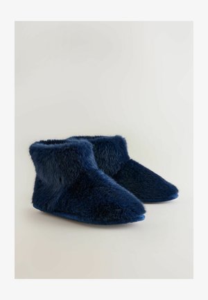 Tamsiai mėlynos dirbtinio kailio aulinukės su švelnia tekstūra, smailiu kulnu ir apvaliu viršutiniu kraštu. Padas lygus ir šiek tiek lenktas.