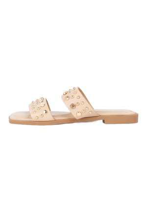 Nude slide sandals with two wide straps, embellished with gold studs and circular accents, featuring a flat rubber sole and smooth texture.