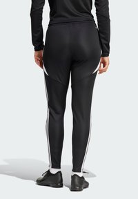 Black athletic leggings with white side stripes, fitted design, smooth texture, worn with black athletic shoes and white socks.