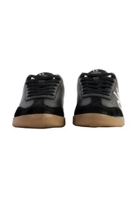 Sneaker nere con finitura lucida, dettaglio del logo bianco e suole in gomma piatta. Presentano un design tradizionale con lacci e colli imbottiti.