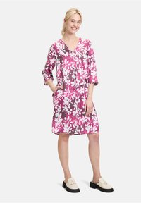 Blumenmusterkleid in Rosa- und lila-Tönen, mit V-Ausschnitt, drei Viertelärmeln und Taschen. Aus leichtem Stoff gefertigt.