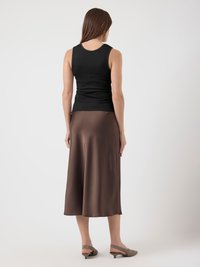 Svart tettsittende tank topp kombinert med en brun sateng midi skjørt, som har en glatt tekstur og en mild flyt, med lys grønne slingback sko.