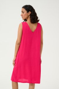 Robe sans manches rose avec un décolleté en V et un dos, fabriquée en tissu léger, présentant une coupe décontractée et une longueur au genou.