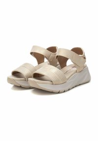 Sandalias de cuña beige con un diseño de tira perforada, que cuentan con anchas correas elásticas en el tobillo y una suela texturizada para mayor agarre.