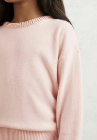 Helles rosa gestricktes Sweatshirt mit rundem Halsausschnitt, ausgestattet mit einem strukturierten Rippbesatz und entspannter Passform. Weicher, leichter Stoff.