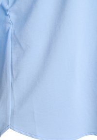 Light blue fabric close-up showing smooth texture with a seam and slight wrinkles.