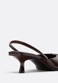 Brauner Slingback-Schuh mit glänzender Lederstruktur, spitzer Spitze, schlankem Absatz und einem Riemen hinten zur Unterstützung.