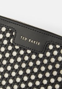 Zwart geweven patroon met een crème achtergrond, voorzien van leren accenten en een gouden logo "TED BAKER" bovenop, beveiligd met een ritssluiting.