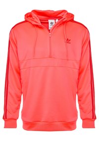 Sweatshirt à capuche rose avec une fermeture éclair quart de longueur, présentant des bandes latérales rouges, des poignets à côtes et un ourlet, fabriqué en tissu lisse et léger.