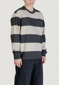 Maglietta a maniche lunghe a righe in grigio scuro e beige con tasca frontale, collo rotondo e polsini a costine. Realizzata in tessuto morbido e traspirante.