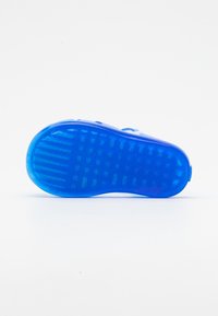 Suela de zapato de goma azul con patrón de agarre texturizado, con bordes redondeados y orificios de ventilación. Acabado suave, diseño ligero.