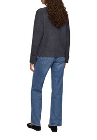 Grau gestrickter Pullover mit gerippten Bündchen, kombiniert mit hellblauen, geraden Jeans. Der Pullover hat ein strukturiertes Muster und eine lockere Passform.
