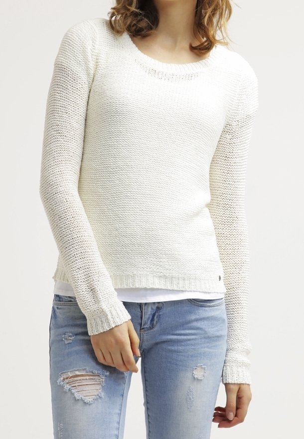 Lehký pletený svetr v mléčně bílé barvě, s kulatým výstřihem, dlouhými rukávy a žebrovanými manžetami, doplněný o roztrhané modré džíny.
