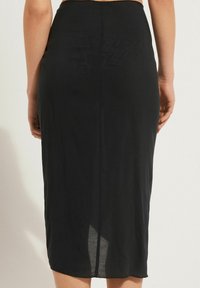 Jupe midi noire en matériau léger, dotée d'une silhouette ajustée, d'une fente à l'arrière et d'une texture lisse. Pas de motifs ni d'accents visibles.