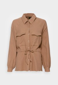 Bruine getextureerde shirt met lange mouwen, kraag, twee borstzakken en verstelbare strik in de taille, met knoopsluiting aan de voorkant.