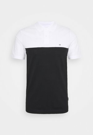 Camisa polo en blanco y negro con un diseño partido. Mangas cortas, cuello con solapa y un pequeño logo de la marca en la esquina superior izquierda. Material de mezcla de algodón.
