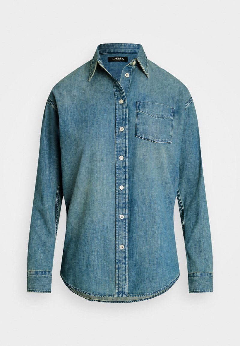 Denimskjorte i falmet blå med knappefront, spiss krage og én brystlomme. Lange ermer med knappemansjetter og buet nederkant.