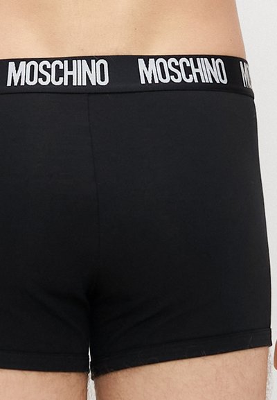 Čierne boxerky s mäkkou textúrou a širokým elastickým pásom. Pás má biele logo "MOSCHINO".