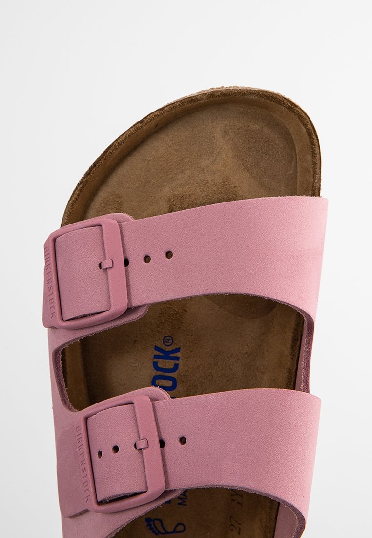 Rosa Birkenstock-Sandale mit zwei verstellbaren Riemen und Schnallen, ausgestattet mit einem geformten braunen Fußbett mit sichtbaren Markenkennzeichnungen.