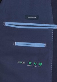 Marineblauer Stoff mit hellblauen Akzenten, ausgestattet mit zwei Reißverschluss-Taschen und umweltfreundlichen Etiketten, die recycelte Inhalte und Nachhaltigkeit kennzeichnen.