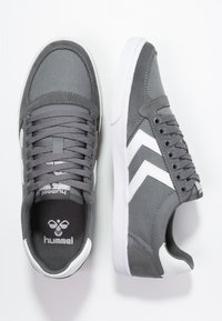 Sneakers in tela grigia con dettagli bianchi e logo. Design low-top, punta rotonda e materiale texturizzato. Lacciati con sei occhielli.