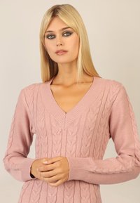 V-Ausschnitt Strickpullover in sanftem Pink mit Zopfmuster und gerippten Bündchen. Glatte Textur, figurbetonter Schnitt und lange Ärmel.