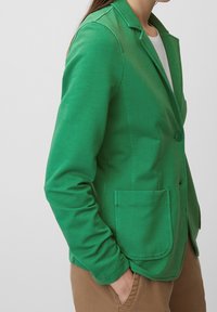 Zelený bavlněný blazer s propracovaným designem, zapínání na jeden knoflík, dvě přední kapsy a límec s výstřihem. Hladká textura a přiléhavý střih.