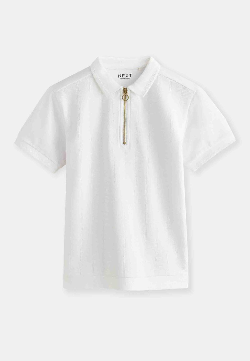Polo shirt blanc à manches courtes avec un design texturé, doté d'une fermeture éclair et d'un col élégant. Agrémenté d'une tirette en métal doré.
