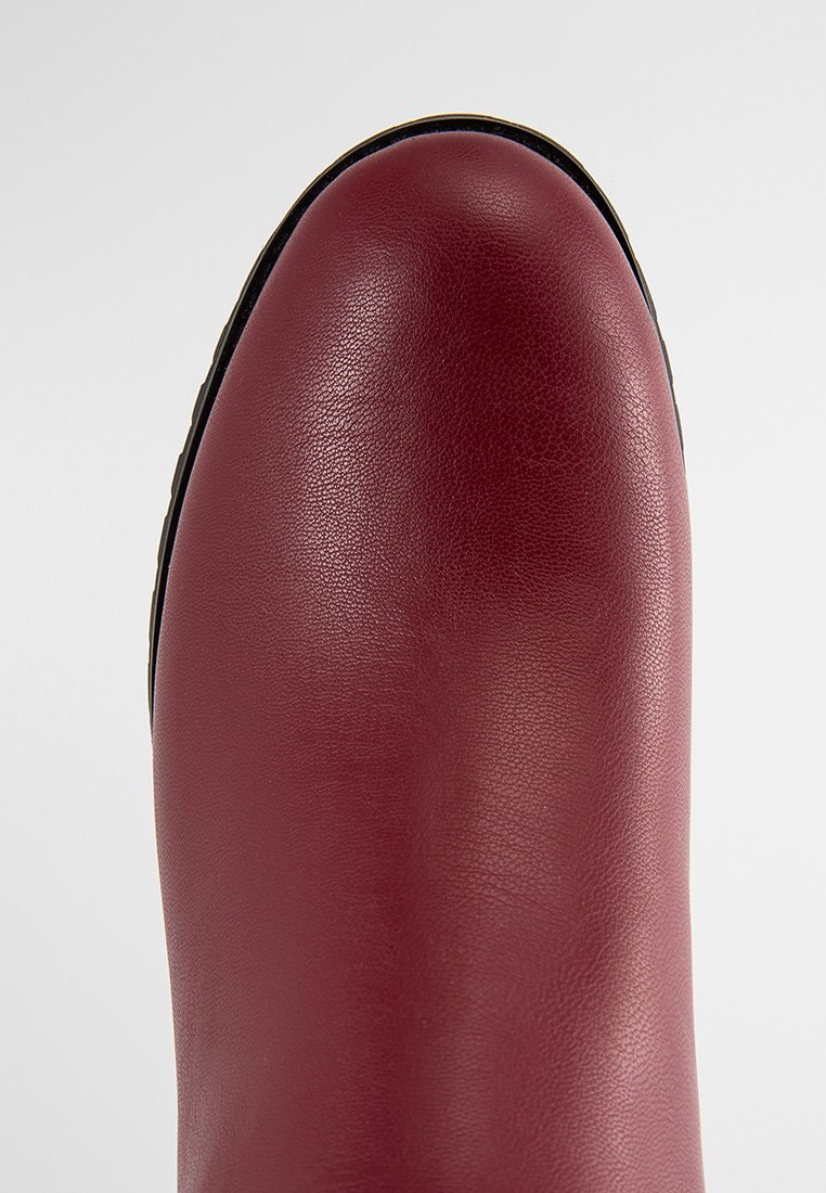 Stivale alla caviglia in pelle bordeaux con una finitura liscia, punta arrotondata e dettaglio della suola nera. Senza hardware o decorazioni visibili.