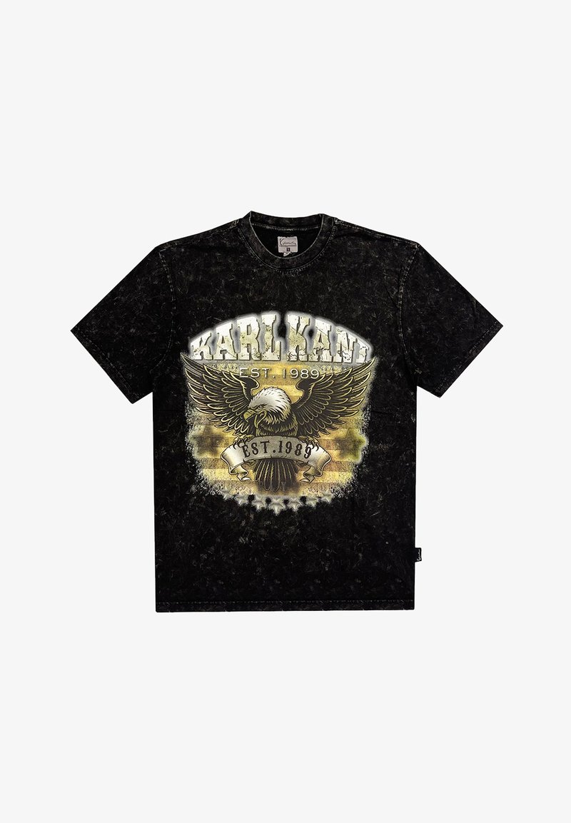 Juodas marškinėliai su apvaliu kaklu, kuriuose yra grafiką vaizduojantis erelį ir tekstą "KARL KANI EST. 1989" auksinės ir baltos spalvų. Minkšta tekstūra.