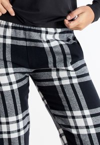 Pantalones de cuadro en negro y gris con una textura suave, que cuentan con una amplia cinturilla elástica y bolsillos laterales para mayor practicidad.