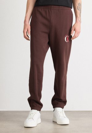 Pantalons de survêtement bordeaux avec taille élastique et chevilles resserrées. Présente un logo Calvin Klein blanc sur la cuisse gauche. Fabriqué en tissu doux.